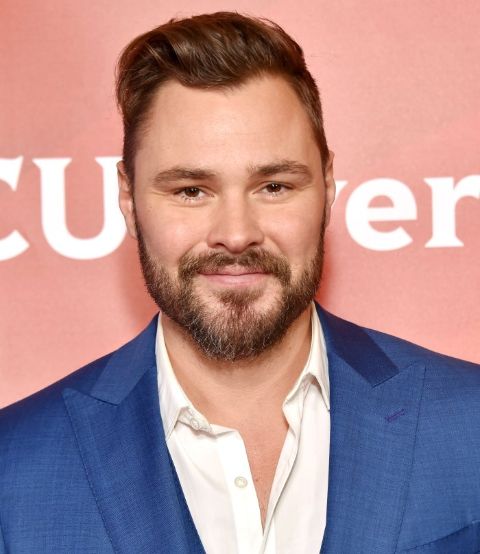 Patrick Flueger in a blue suit poses for a picture.
